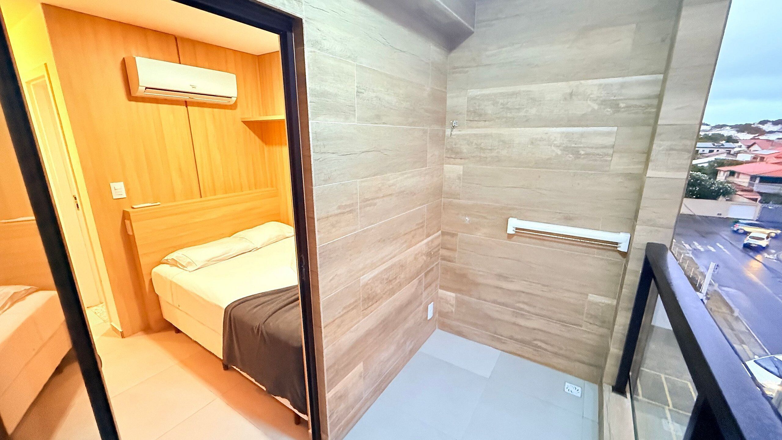 A small, modern room with a bed, a wooden wardrobe, and a shower area.