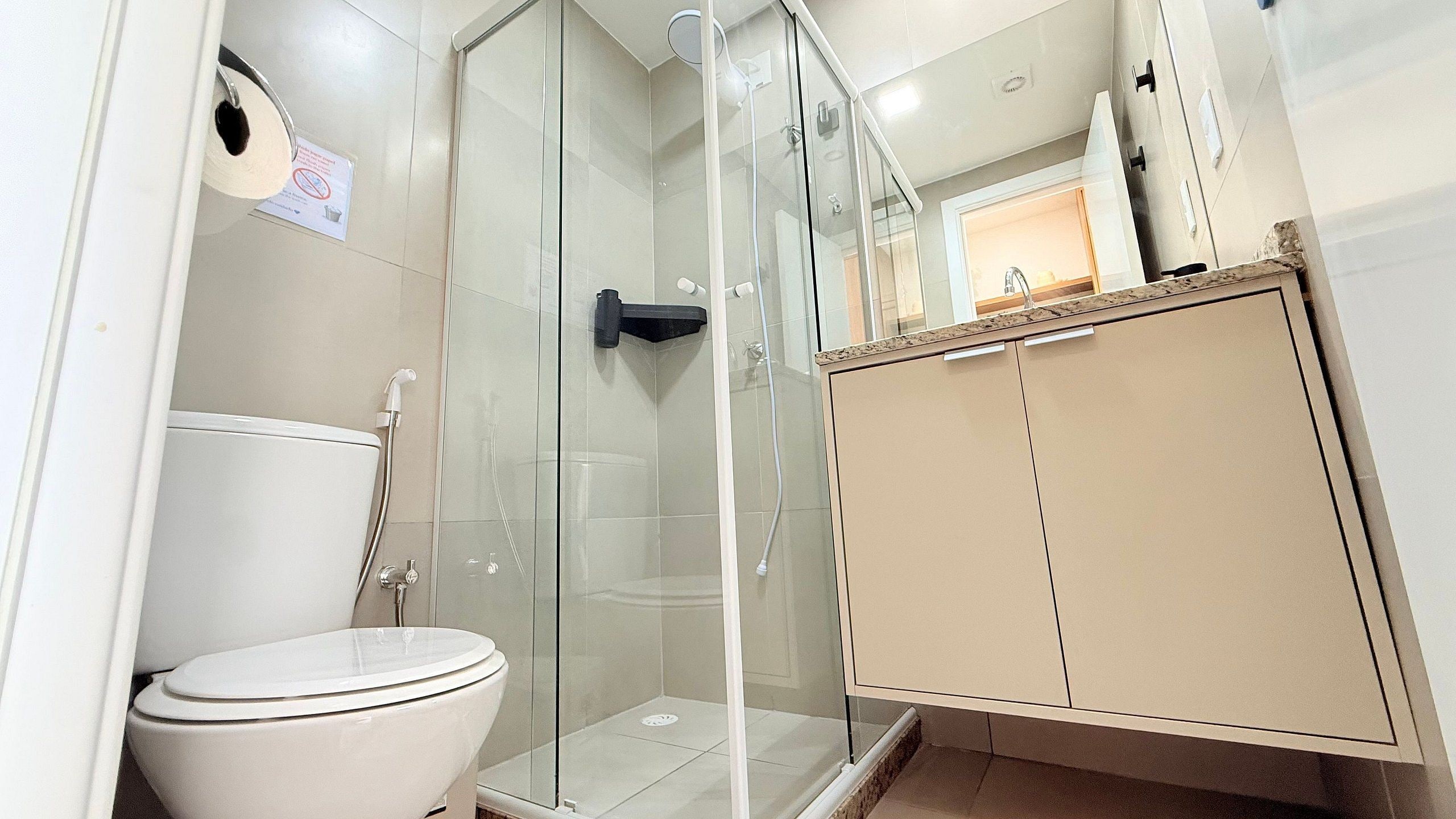 Une salle de bain comprenant des toilettes, une douche en verre et un meuble de rangement.
