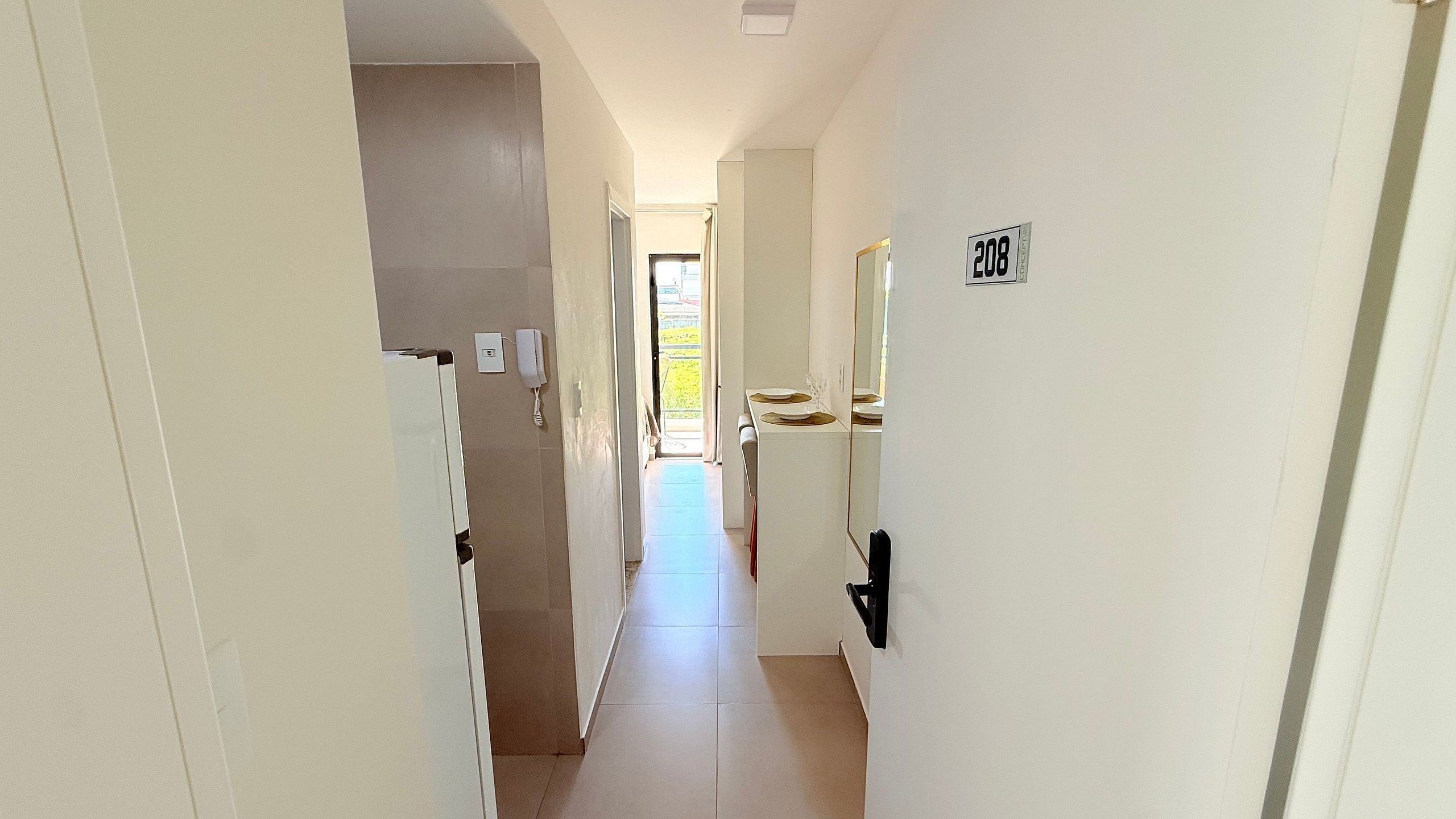 A narrow hallway with a door labeled '208' leading to a room with a window.