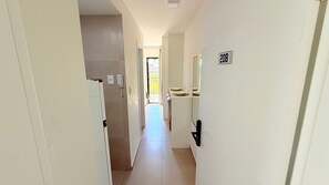 A narrow hallway with a door labeled '208' leading to a room with a window. - Concept Life Stella (Salvador)