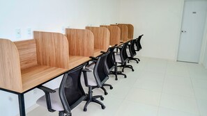 Una sala de conferencias con paneles de madera, sillas de oficina negras y una puerta blanca.