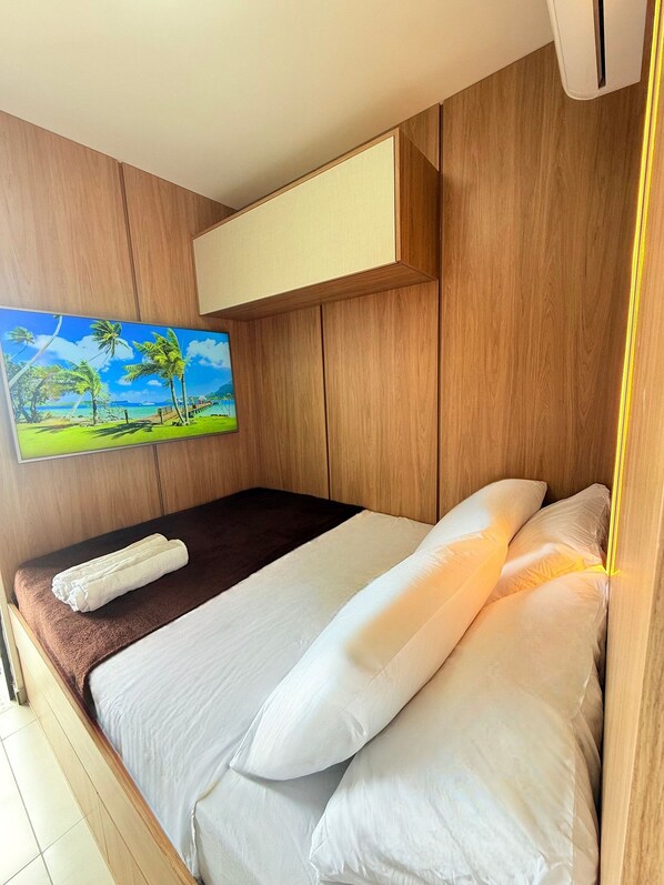 Habitación de hotel con una cama, un cuadro de una playa tropical y un cabecero de madera.