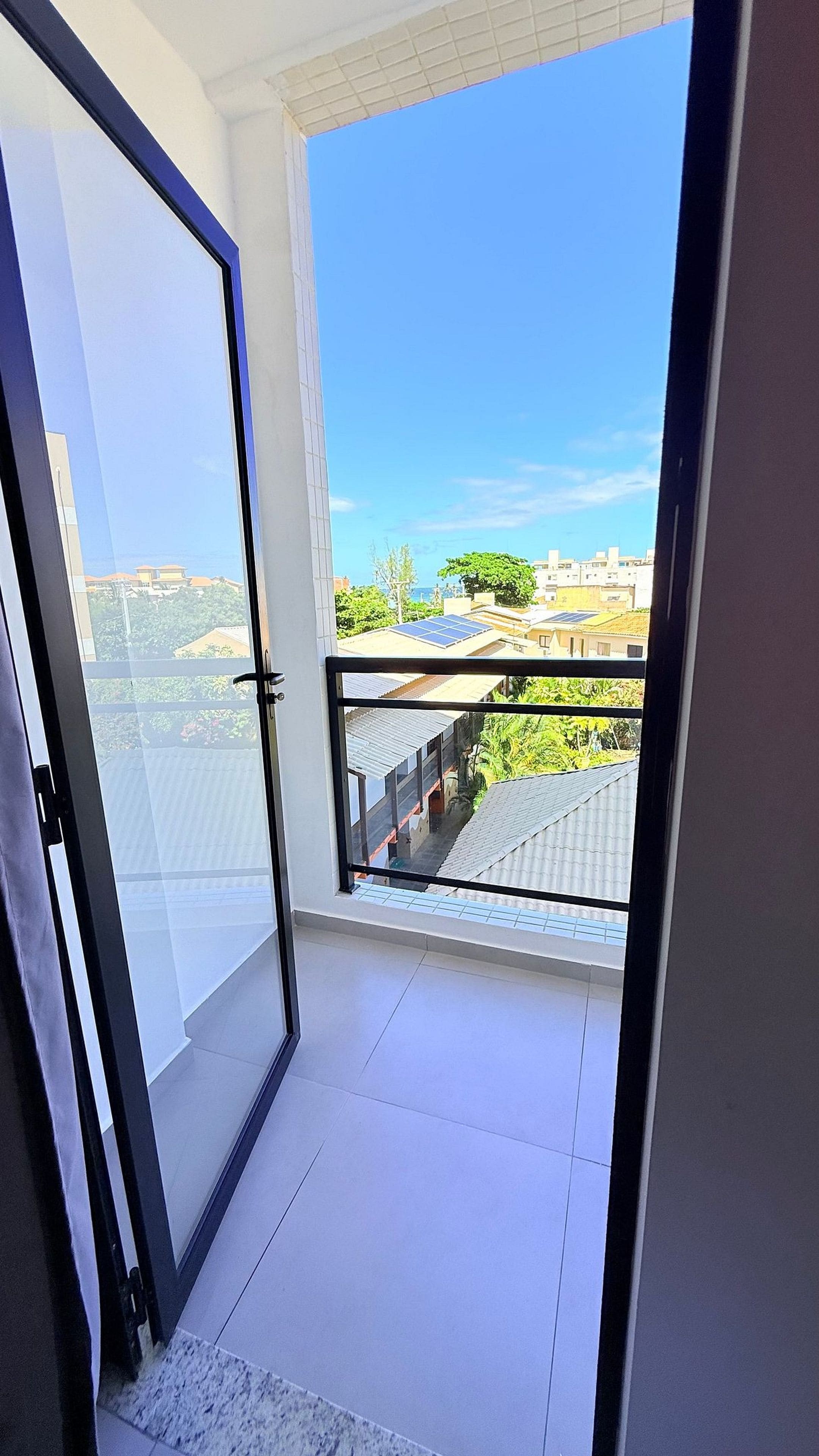 Un balcone aperto con vista libera su edifici e vegetazione.