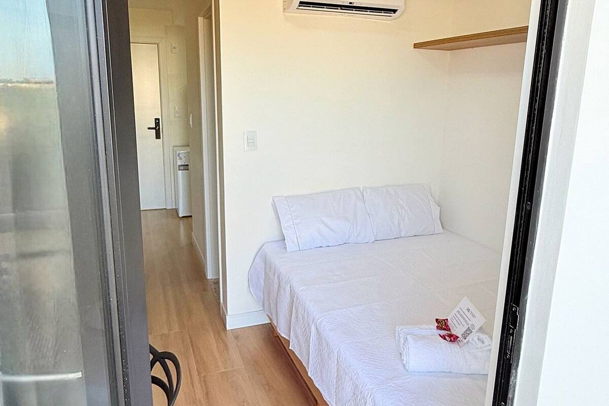 Un dormitorio con una cama, un equipo de aire acondicionado y una puerta que da a otra habitación.