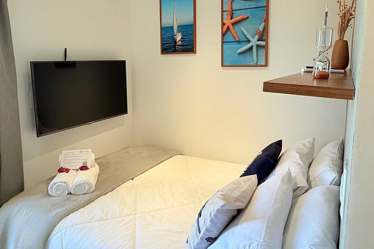 Un dormitorio moderno con cama, televisor de pantalla plana, obras de arte y aire acondicionado integrado.