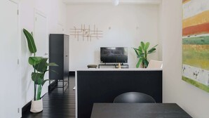 A modern living room with a black sofa, a TV, and a decorative wall piece. - Bright & Cozy Studio in Mechelen (Mechelen)