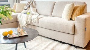Ein modernes Wohnzimmer mit einem beigefarbenen Sofa, einem runden Couchtisch und abstrakter Wandkunst.