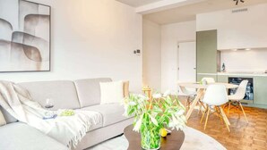 Ein modernes Wohnzimmer mit einer Couch, einem Couchtisch mit Blumen und einem Essbereich mit Stühlen und Tisch.