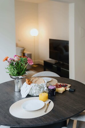 Ein Esstisch mit verschiedenen Speisen, einer Blumenvase und einem Fernseher im Hintergrund.