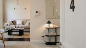 A modern living room with a sofa, coffee table, and a lamp. There is a staircase leading to another level, and a door with the number 4. - Stylish Duplex Getaway in the Heart of Antwerp (Antwerpen)