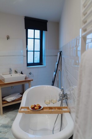 Ein Badezimmer mit freistehender Badewanne, einem Fenster, einem Waschbecken und einem Handtuchhalter.