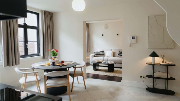 A modern living room with a round dining table, two sofas, a coffee table, and a TV. - Stylish Duplex Getaway in the Heart of Antwerp (Antwerpen)