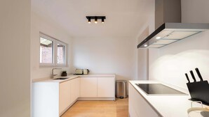 Eine moderne Küche mit weißen Schränken, einem Backofen, einer Spüle und einem Fenster.