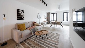 Ein modernes Wohnzimmer mit Sofa, Couchtisch und Essbereich mit Tisch und Stühlen.