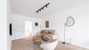 Ein modernes Wohnzimmer mit Sofa, Sessel, Couchtisch und Stehlampe.