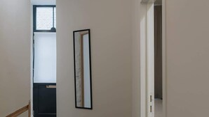 A hallway with dark wooden flooring, white walls, and a framed picture on the wall. - Spacious 3-Level Apartment in Mechelen (Mechelen)