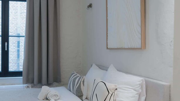 A modern hotel room with a large bed, a bedside table, and a window with curtains. - Spacious 3-Level Apartment in Mechelen (Mechelen)