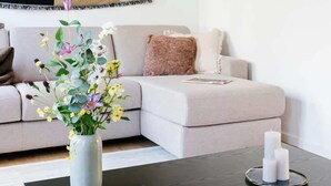 En moderne stue med en sofa, et sofabord og en vase med blomster.