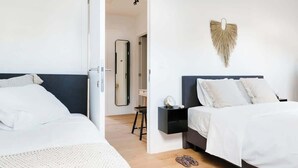 A bedroom with two beds, a bedside table, a mirror, and a wall-mounted decorative item. - Magnificent 3BR home in Antwerp (Antwerpen)