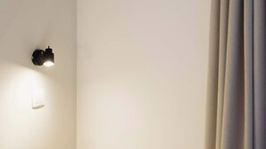 Ein Zimmer mit einer Decken-Klimaanlage, einer Wandleuchte und einem Vorhang auf der rechten Seite.