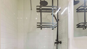 Ein modernes Badezimmer mit einer gläsernen Duschkabine, einem weißen Waschbecken und einem Spiegel darüber.