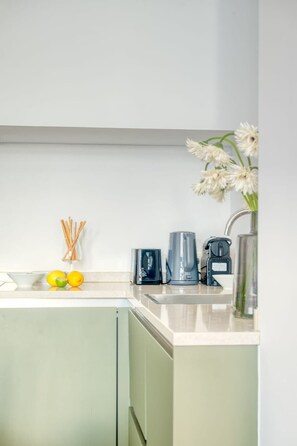 A kitchen with a white countertop, a coffee maker, a glass container, and a vase with flowers. - Cozy Retreat in Antwerp with balcony (Antwerpen)