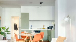 En moderne stue med spiseplads, et køkken og et hyggeligt opholdsområde med en gyngestol.