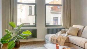 En moderne stue med en sofa, et sofabord og en potteplante.