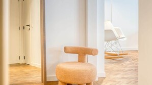 A modern interior with a wooden floor, a unique textured chair, and a minimalist design.