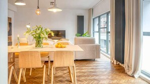 A modern living room with a dining area, large windows, and a sofa.