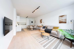 Ein modernes Wohnzimmer mit einer Couch, einem Couchtisch und einem Essbereich mit Stühlen.