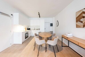 Eine moderne Küche mit weißen Schränken, einem runden Holztisch und sechs Stühlen.