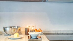 A kitchen counter with a large mixing bowl, a small bowl with butter, a scale, and a candle. - Bright 2BR Flat in Antwerp City (Antwerpen)