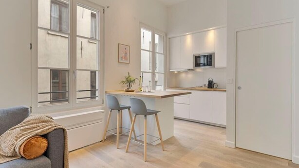 A modern kitchen with white cabinets, a central island with bar stools, and a microwave above the island. - Chic 1-BR in Antwerp's Center (Antwerpen)