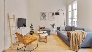 A modern living room with a sofa, coffee table, and a TV on a white console. - Chic 1-BR in Antwerp's Center (Antwerpen)