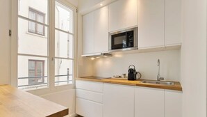 A modern kitchen with white cabinetry, a wooden countertop, a built-in microwave, and a sink. - Chic 1-BR in Antwerp's Center (Antwerpen)