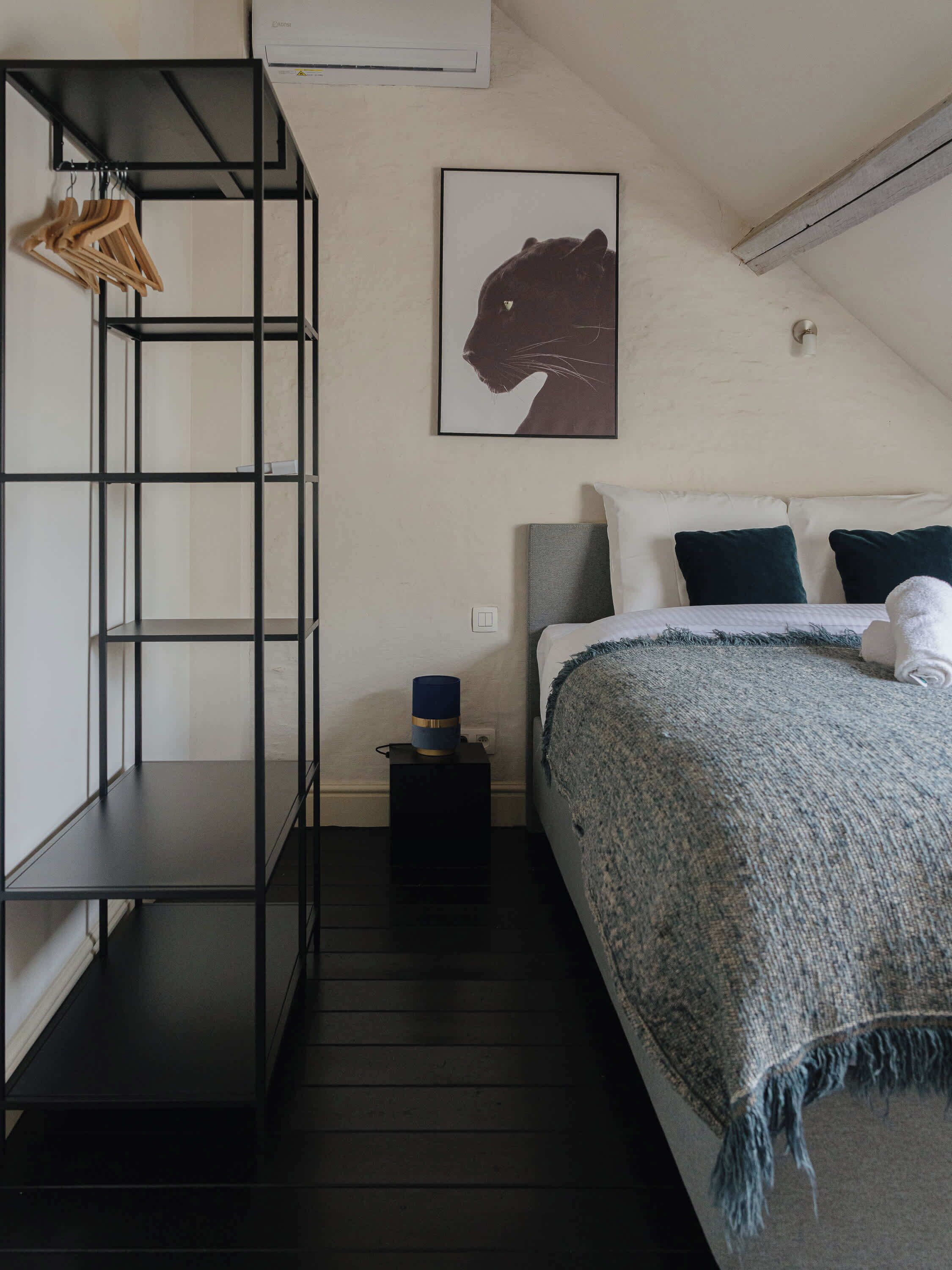 Une chambre avec un lit superposé, un portrait d’animal encadré accroché au mur, une table de chevet avec une lampe et un plancher en bois foncé.