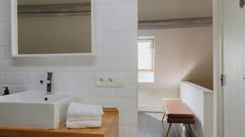 Une salle de bain moderne avec un lavabo blanc, un miroir et un banc en bois.