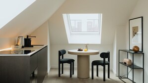 A modern kitchen with a dining area, a coffee machine, and a round table with chairs. - Elegant and Spacious Suites (Antwerpen)