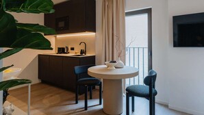A modern kitchen with dark cabinets, a round dining table, and two blue chairs. - Elegant and Spacious Suites (Antwerpen)