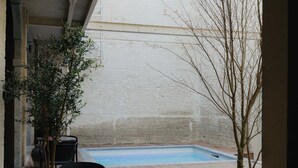 Un patio con piscina, mobili da esterno e vista su un edificio sullo sfondo.