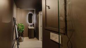 Un bagno moderno con doccia in vetro, lavandino con specchio e una pianta in vaso.