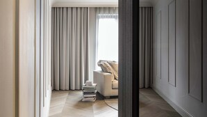 Een moderne woonkamer met een bank, een stapel boeken en een groot raam met gordijnen.