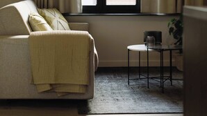 Una habitación con sofá, una mesita y una ventana con cortinas.