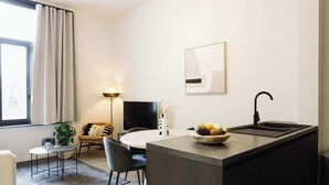 Una cocina moderna con una isla central, un comedor con sillas, un sofá y un televisor.