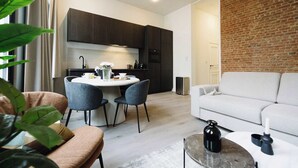 A modern living room with a white sofa, a coffee table, and a dining area with a white table and chairs. - Bright 1-Bedroom Apartment with Balcony in Antwerp (Antwerpen)