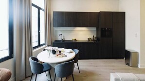 A modern kitchen with dark cabinets, a round dining table with chairs, and a small refrigerator. - Bright 1-Bedroom Apartment with Balcony in Antwerp (Antwerpen)