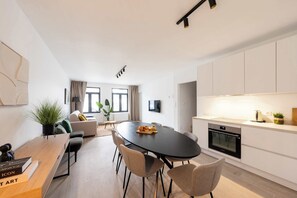 Una cocina moderna con comedor, muebles blancos y horno empotrado.