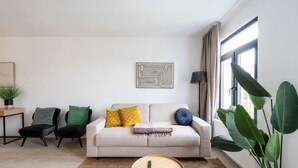Uma sala de estar com sofá, duas poltronas, mesa de centro, abajur e uma planta grande.