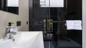 Un bagno moderno con una vasca da bagno bianca di grandi dimensioni, una doccia con pareti in vetro e un asciugamano bianco su un portasciugamani.
